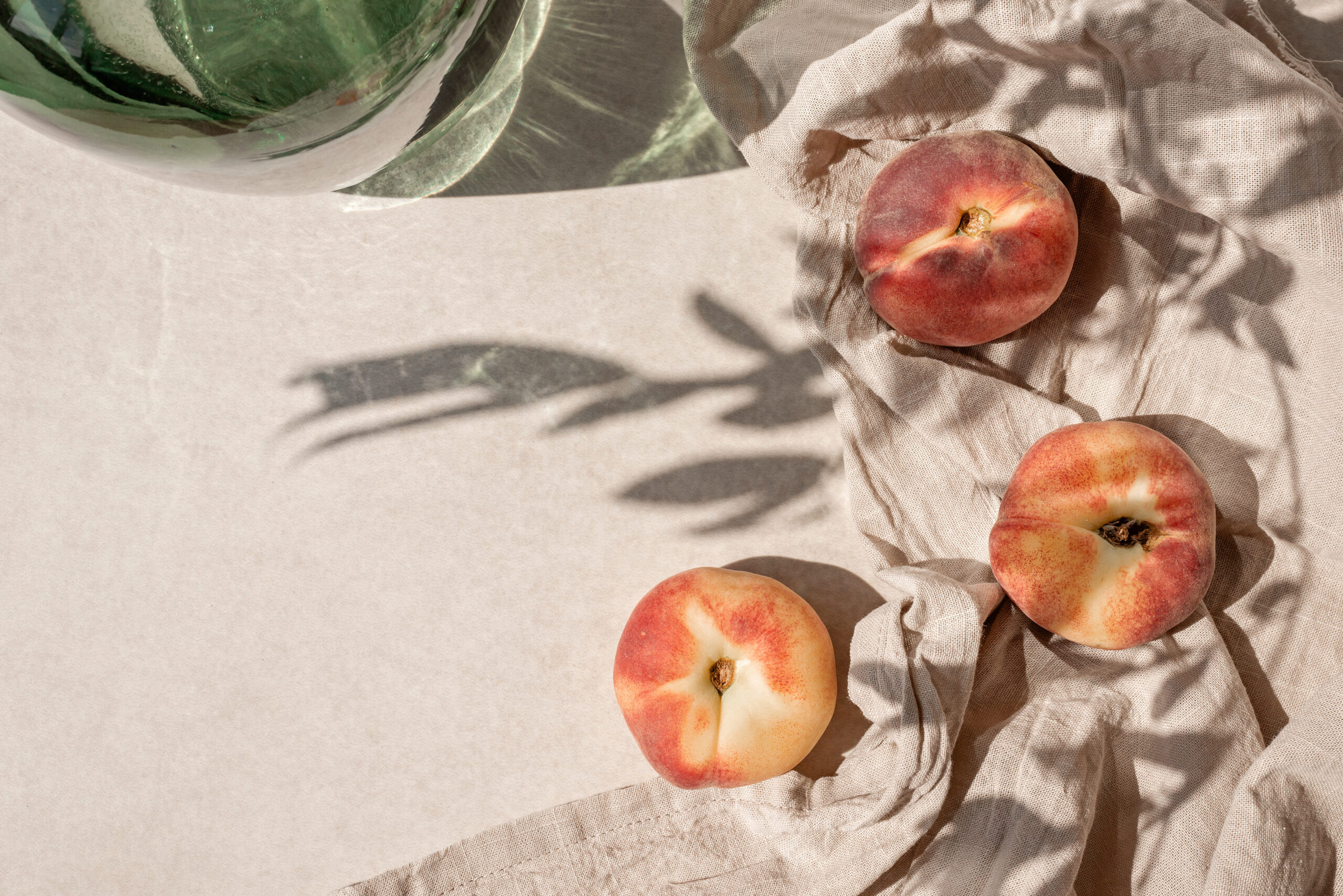 Aesthetic lifestyle fruit pattern with peaches, crumpled linen fabric and floral sunlight shadow on a beige table background